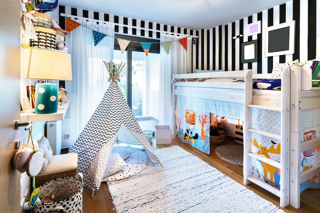 Kids playroom with bunk wooden bed, teepee, stands, carpet frames and toys.
