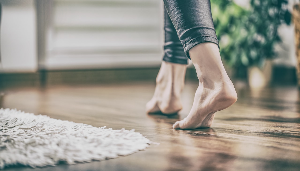 woman walking on hardwood flooring with a rug