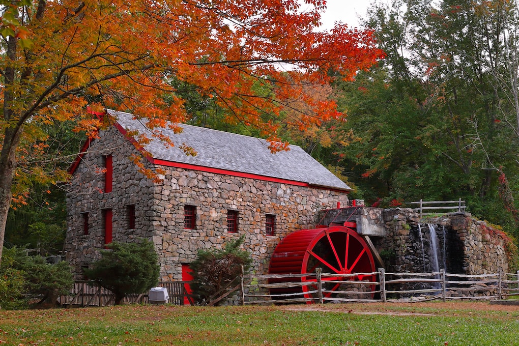 The Wayside Inn Grist Mill with water wheel and cascade water fall in Autumn.