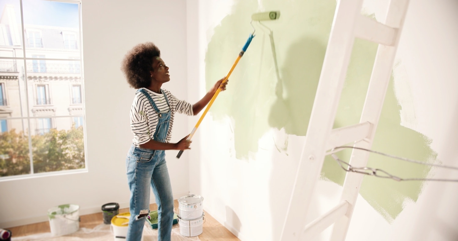 young woman paints her bedroom as a home remodeling project