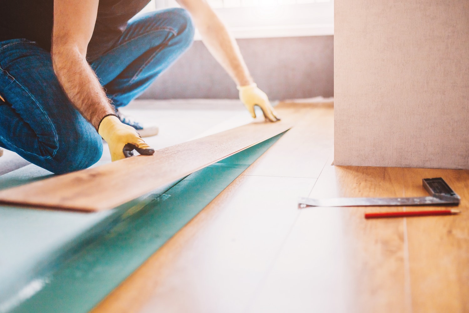 Man at home laying laminate flooring - finishing home remodeling