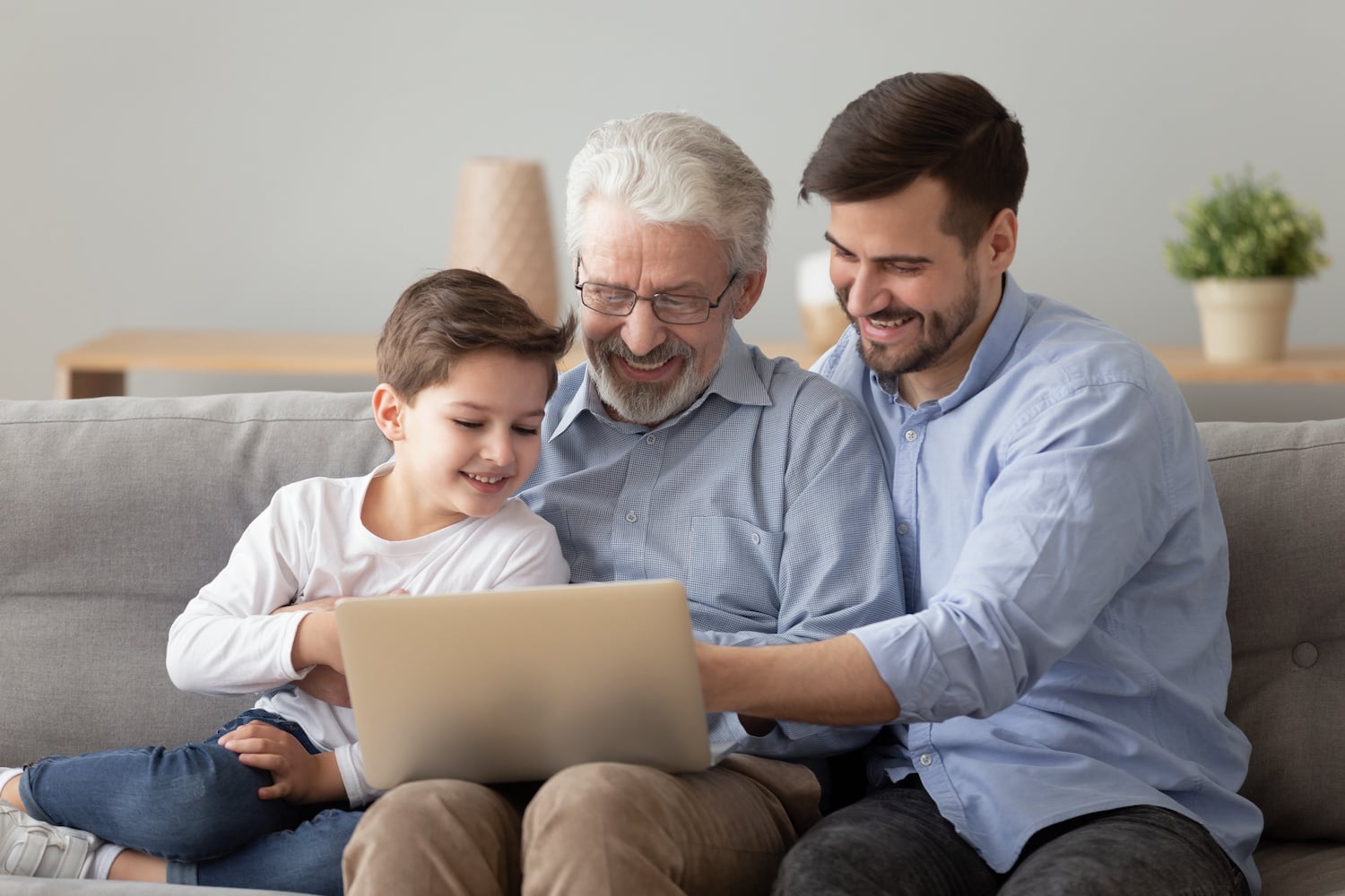 multigenerational homes three generations of family looking at laptop together and smiling